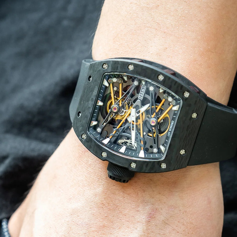 Luxury watch with a black strap on a person's wrist against a dark background