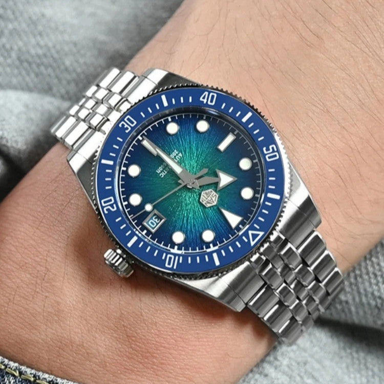 Silver watch with a blue face on a wrist, wearing a denim jacket.