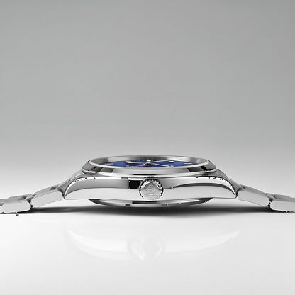 Close-up of a silver watch with a blue face on a lighat gray background