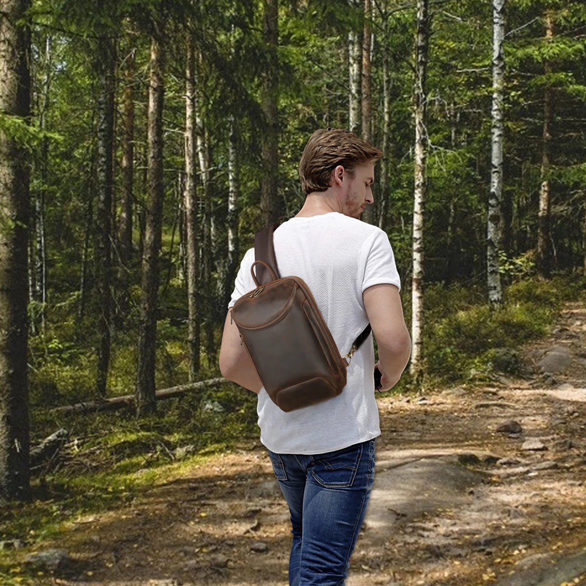 Men's Crazy Horse Leather Tablet Sling Bag — worn on the back by a man in a white T-shirt on a forest trail