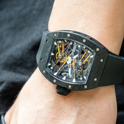 Luxury watch with a black strap on a person's wrist against a dark background