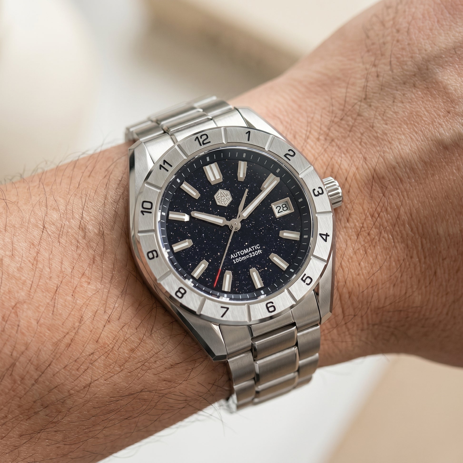 San Martin SN0130GB - Silver wristwatch with a dark face on a wrist against a neutral background