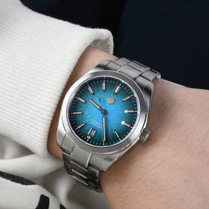 Silver watch with a blue face on a wrist, wearing a white sweater.