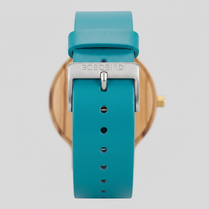 Teal watch with gold case and Bobo Bird branding on a light gray background