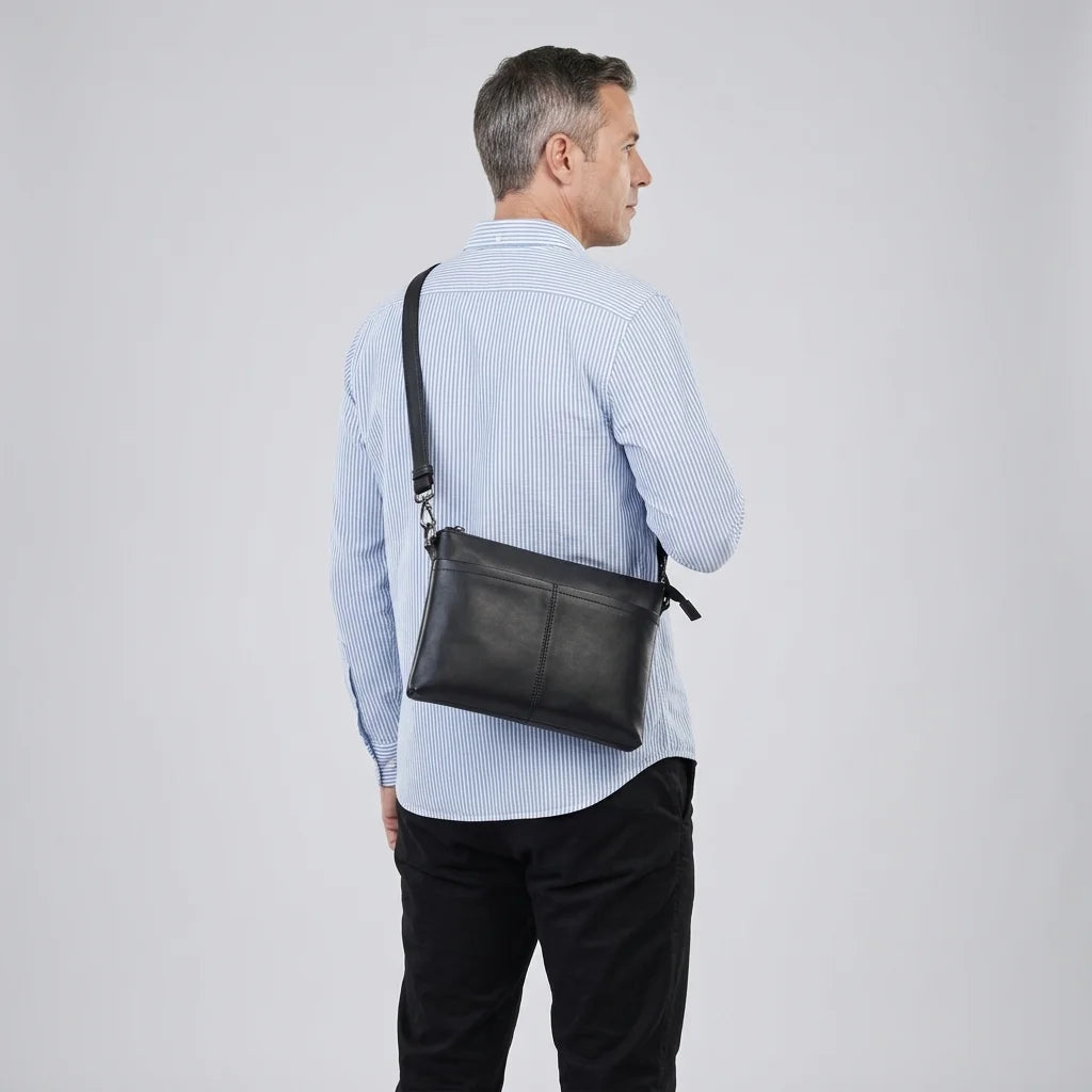 Men's Slim Black Leather Crossbody Bag — worn crossbody by a man in a light blue shirt, back view