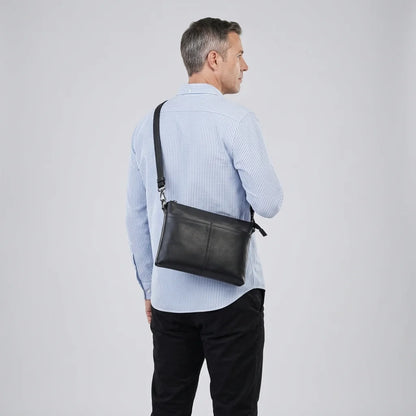 Men's Slim Black Leather Crossbody Bag — worn crossbody by a man in a light blue shirt, back view