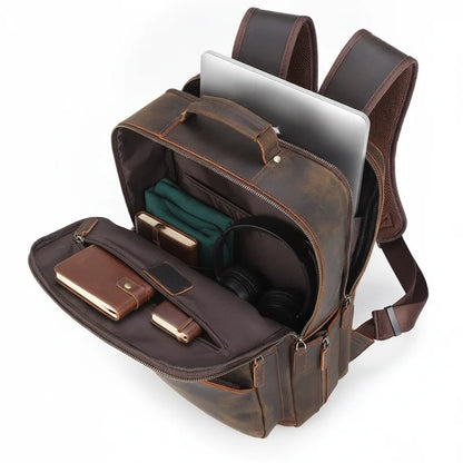 Men's Leather Travel Laptop Backpack — open main compartment with laptop, notebook, headphones and pouch