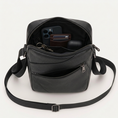 Men's Full-Grain Leather Compact Crossbody Messenger Bag — open from above with a phone, wallet, keys and earbuds case inside