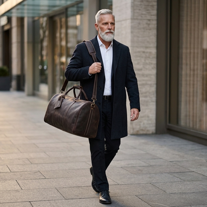 Men's Full-Grain Leather Duffle Bag with Luggage Tag — carried over the shoulder by a man in a dark overcoat