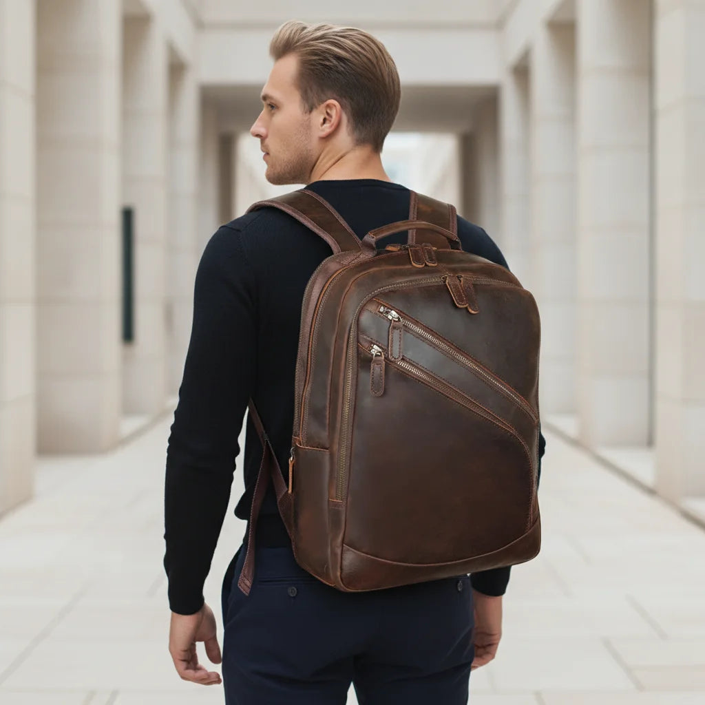 Leather Multi-Pocket Travel Backpack — worn on the back by a man in a black sweater